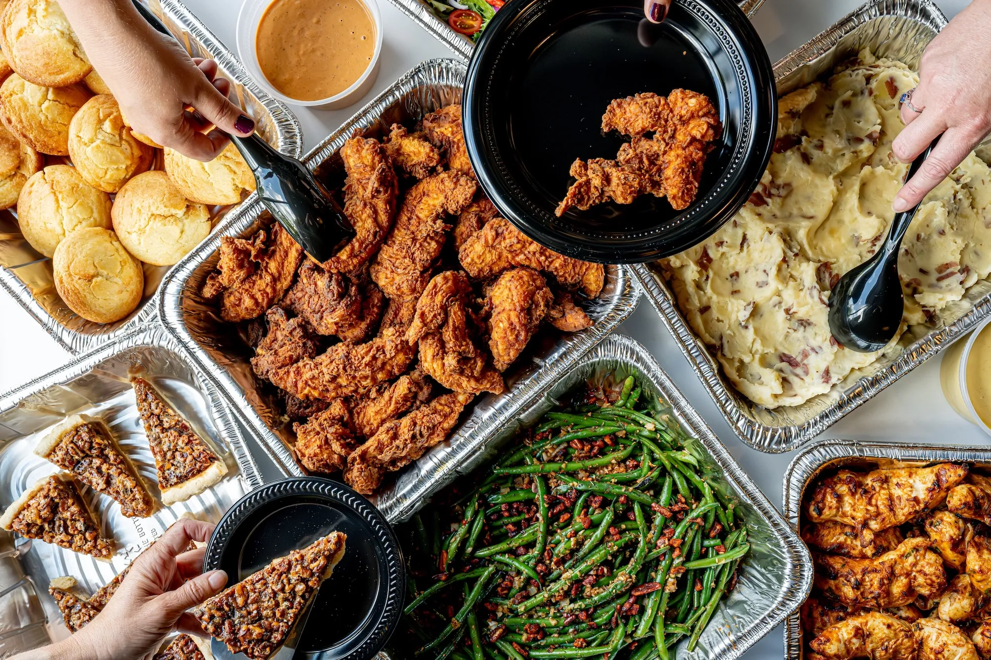DSC_7501-Enhanced-NR A full table of food including chicken tenders, potatoes, green beans, bread, and pecan pie